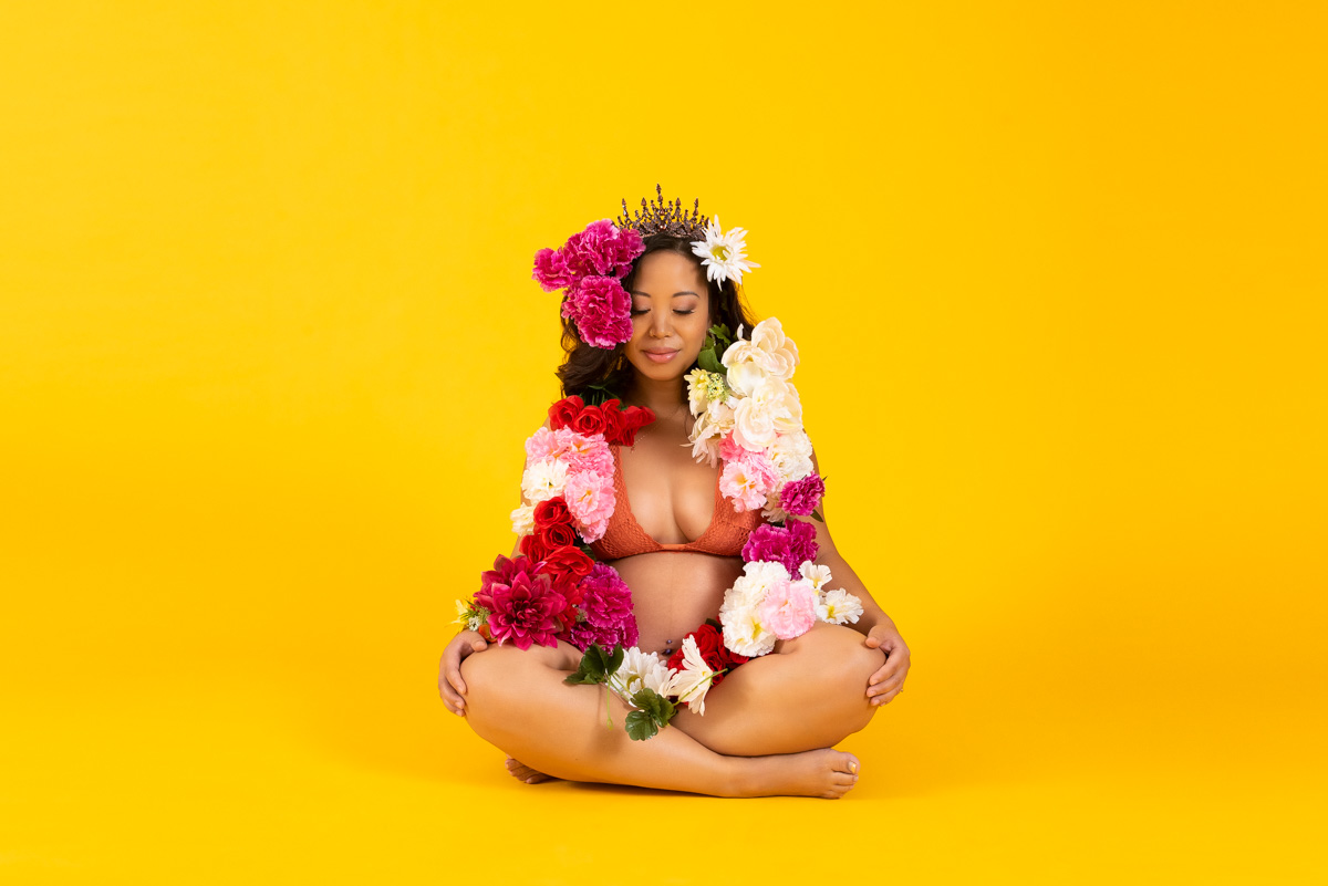 pregnant woman wearing Tiara and surrounded by flowers